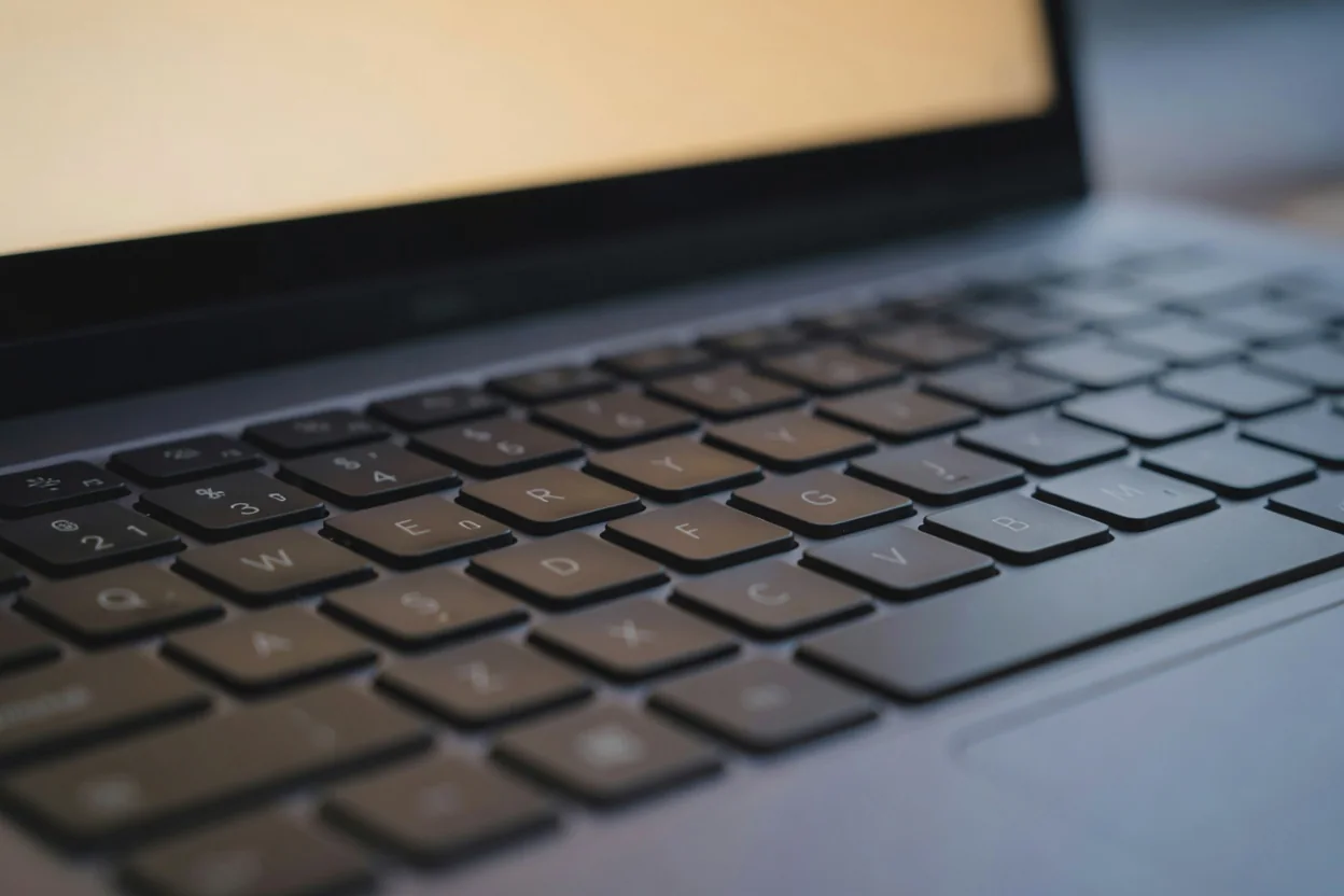 Zbliżenie klawiatury laptopa z ciepłą poświatą ekranu, płytka głębia ostrości