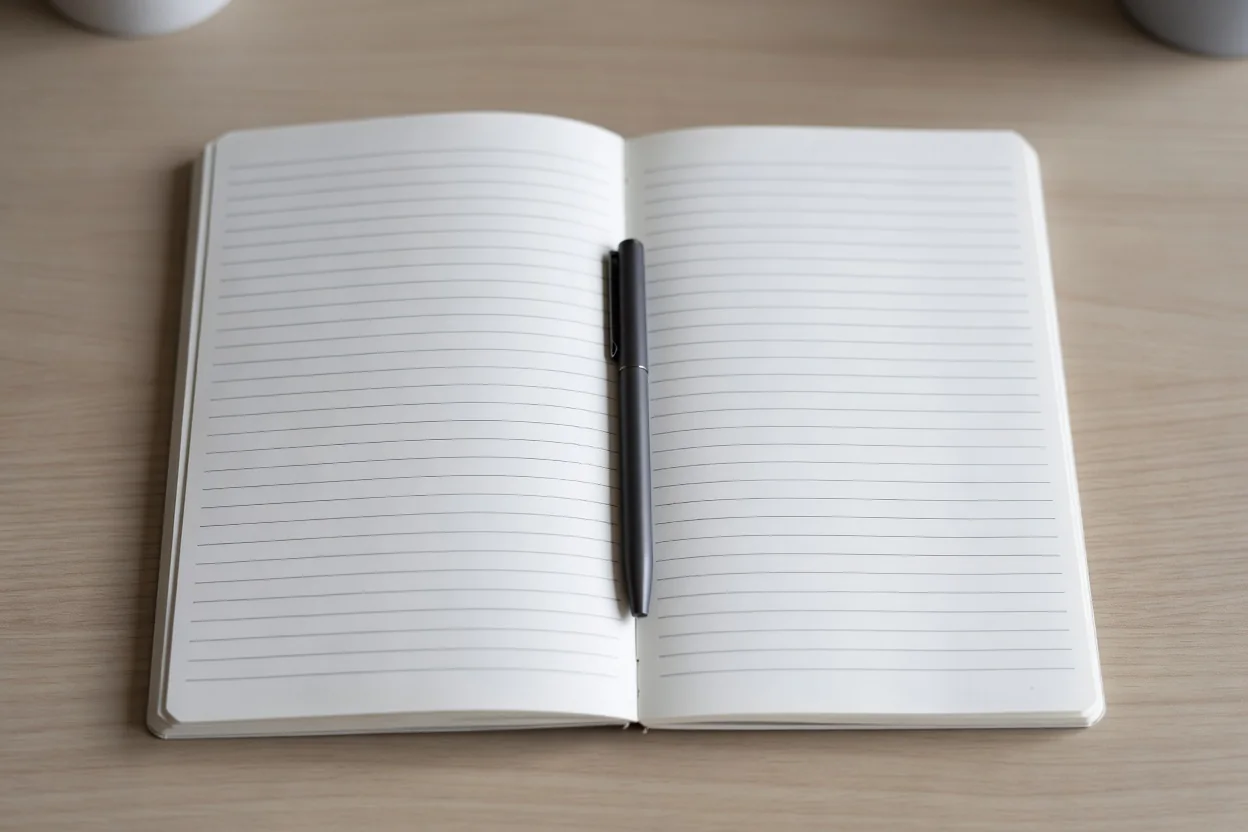 Otwarty pusty notes w linie z szerokimi marginesami i długopisem, widok z góry