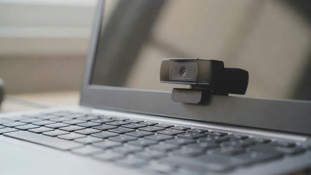 Zbliżenie małej kamery internetowej na ekranie laptopa, klawiatura z przodu, płytka ostrość